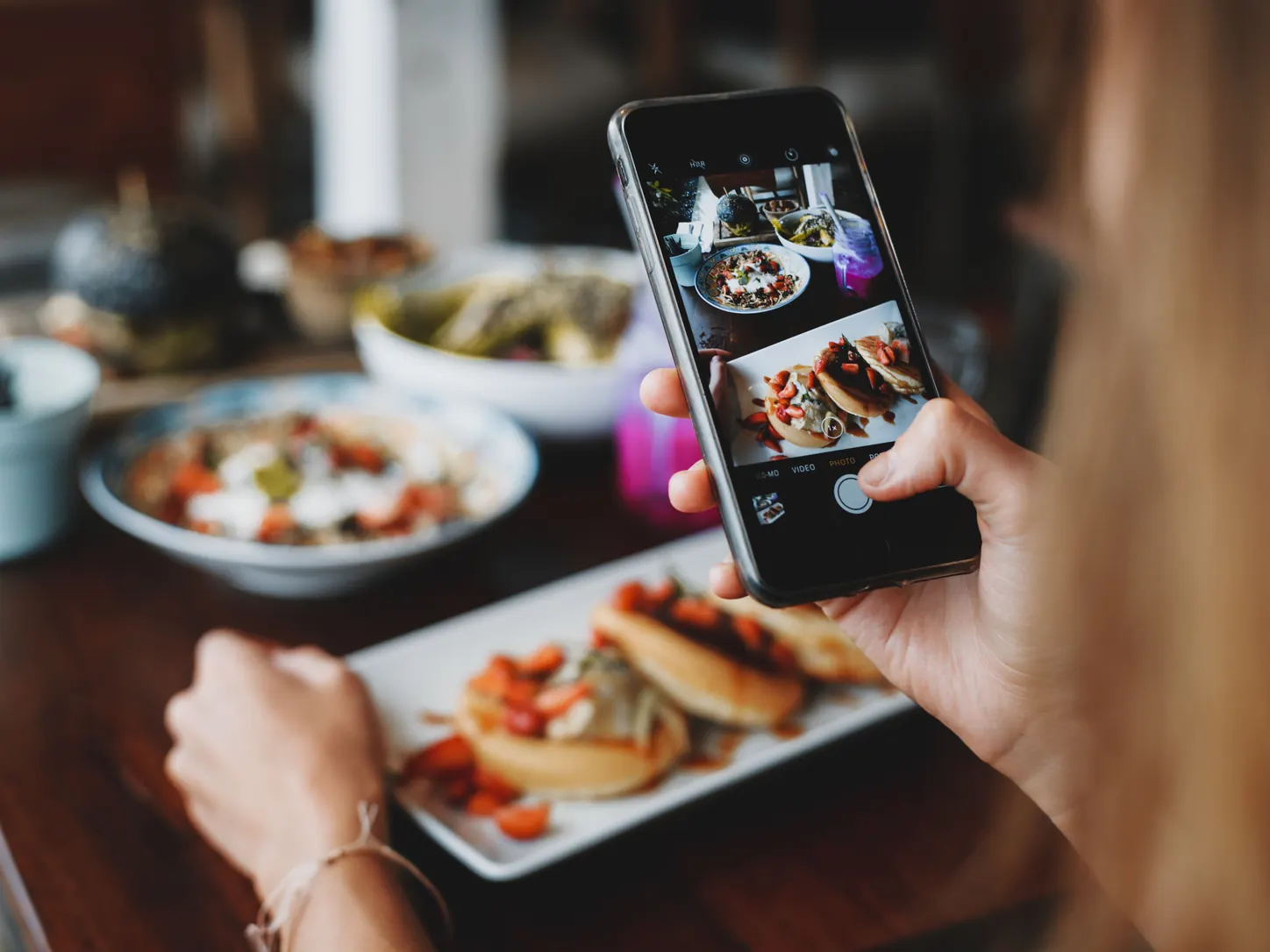 A diner photographing a colorful meal with a phone.
